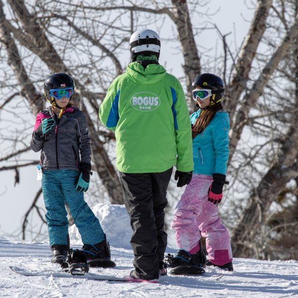 Ski school teaching two snowboarders