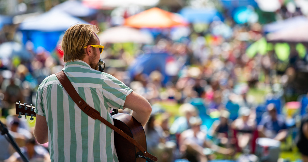 Close Up Of Guitarist With Guests Blurred In The Back Playing Music On The Mountain At Bogus Basin Summer 2021 - Photo By Luke Tokunaga