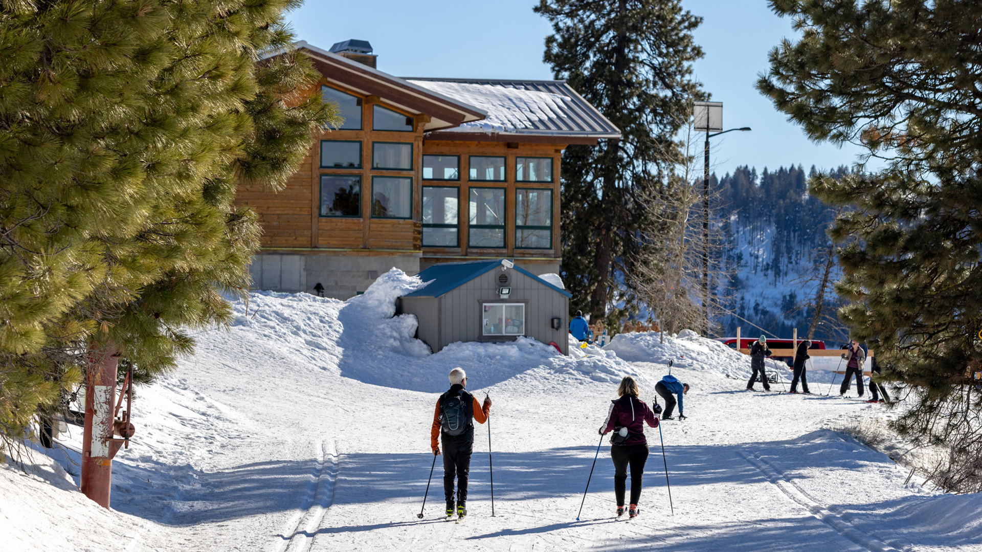 Two Nordic Skiers Returning To Frontier Point Lodge From The Nordic Highway At Bogus Basin Mountain Recreation Area On A Bluebird Day Skating Towards Skiers Preparing To Depart Winter 2022 Photo By Luke Tokunaga 1920px1080px