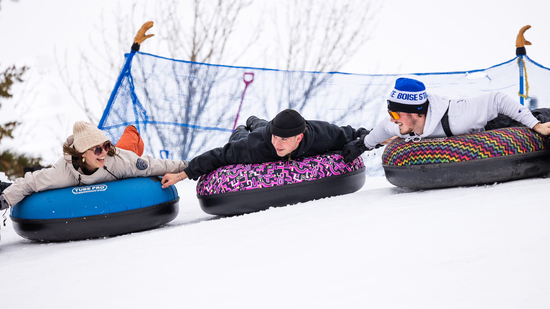 Female And Male College Students Laying On Tubes On Their Stomach Smiling As They Slide Down The Winter Tubing Hill At Bogus Basin Mountain Recreation Area Winter January 2024 Photo By Cassidy Carter 1920px1080px