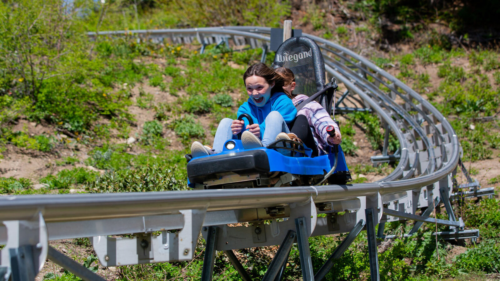 Two Female Children Guests Close Up On Glade Runner Mountain Coaster Mouth Open Smiling Summer At Bogus Basin Mountain Recreation Area 1920px1080px
