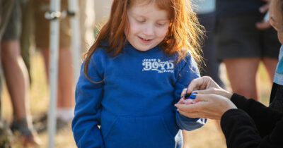 Featured Image Intermountain Employee Handing Hummingbird To Young Child In Blue Sweatshirt For Intermountain Bird Observatory Hummingbird Banding Event At Bogus Basin 07-2024 Photo By Nate Collins 1200px 630px