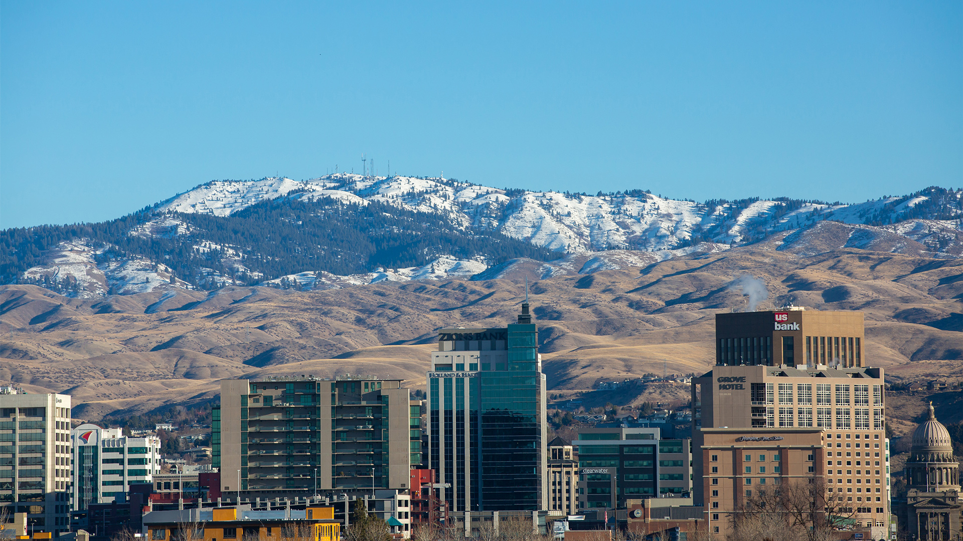 View Of Bogus Basin From Downtown Boise With Buildings In The Foreground And Snow Gathering In The Foothills Winter At Bogus Basin Mountain Recreation Area 1920px1080px