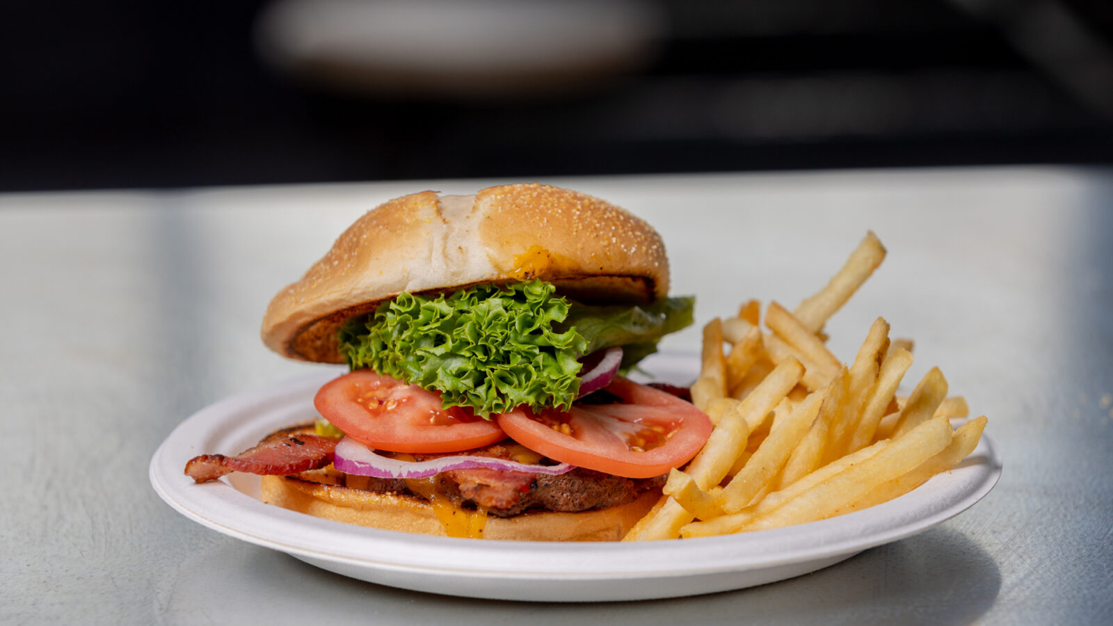 Close Up Of Cheeseburger With Bacon Lettuce Onion And Tomato With French Fries On A Table In Bogus Creek Lodge Winter 2021 Food And Beverage At Bogus Basin Mountain Recreation Area Photo By Luke Tokunaga 1920px1080px